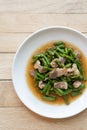 Fried yardlong beans with streaky pork in white dish on wooden table