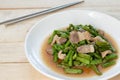 Fried yardlong beans with streaky pork in white dish on wooden table