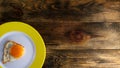 Fried yolk on round ceramic plate with yellow edge on rough wooden background or table. Copy space for text. Top down. Flat lay. Royalty Free Stock Photo