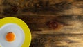 Fried yolk on round ceramic plate with yellow edge on rough wooden background or table. Copy space for text. Top down. Flat lay. Royalty Free Stock Photo