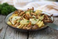 Fried young potatoes with chanterelles mushrooms in bowl on old Royalty Free Stock Photo