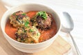 Fried zucchini balls in tomato sauce and parsley garnish in a bowl on a wooden board, healthy vegan or vegetarian meal, copy space Royalty Free Stock Photo