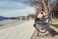 Friedelstrand, south shore WÃÂ¶rthersee, Klagenfurt, Carinthia, Austria - February 20, 2019: A woman sitting on a park bench on an