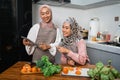 friend with hijab looking at tablet to make new food Royalty Free Stock Photo