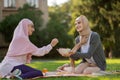 Friend wearing hijab sharing some blueberries with friend