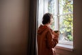 Friendless teen girl standing near window, dreaming of walking in street in warm sunny weather Royalty Free Stock Photo