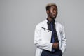Friendly Afro-American doctor holding a clipboard and smiling at the camera on gray Royalty Free Stock Photo