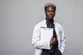 Friendly Afro-American doctor holding a clipboard and smiling at the camera on gray Royalty Free Stock Photo