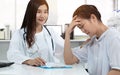 Friendly Asian doctor with smiley face, touching stress patient on shoulder for soothe with gently calm in medical consultation Royalty Free Stock Photo