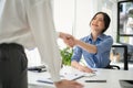 A friendly Asian female HR recruiter is shaking hands with a candidate after an interview