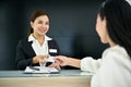 Friendly Asian female receptionist greeting and welcoming a customer with beautiful smile