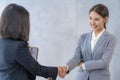 A friendly Asian female recruiter shakes hands with a candidate after an interview. A successful