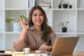Friendly woman office worker greeting colleagues while working with computer laptop. Royalty Free Stock Photo