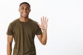 Friendly attractive nice african american male friend raising palm to wave smiling broadly saying hello, greeting