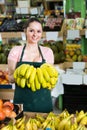 Friendly attractive salesgirl proposing fresh bananas in supermarket Royalty Free Stock Photo