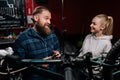 Friendly bearded cycling repairman male having conversation with positive blonde female client, talking about problem of Royalty Free Stock Photo