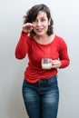 Brazilian, holding a mug of cappuccino, lowering her head, with her hand close to her face and telling a story