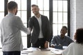 Friendly businessmen shaking hands before negotiation in modern office