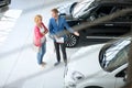Friendly car dealer showing young women new car Royalty Free Stock Photo