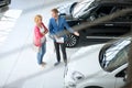 Friendly car dealer showing young women new car