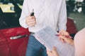 Friendly car salesman talking to a young woman and showing a new car inside showroom Signing of contract. Royalty Free Stock Photo