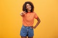 Friendly carefree and happy good-looking tall african american female model with curly hairstyle holding hand on hip