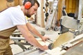 friendly carpenter with ear protectors and working clothes working on a saw in the workshop Royalty Free Stock Photo