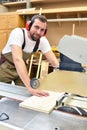 friendly carpenter with ear protectors and working clothes working on a saw in the workshop Royalty Free Stock Photo