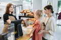 Friendly cashier handing pastry goods in a bag to mom with a daughter.