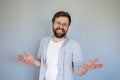 Friendly, charming man smiles cute and makes a gesture with hands. Gray background.