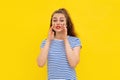 Friendly cheerful brunette girl shouting out loud, combined hands in a megaphone, standing in white-blue striped t shirt over Royalty Free Stock Photo