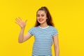 Friendly cheerful brunette girl smiling, saying hi and waving hand to greet person, make hello gesture, welcome someone, standing Royalty Free Stock Photo