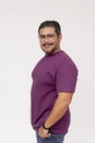 A friendly chubby man of mixed ancestry wearing glasses. Half body photo, quarter turn pose, wearing purple waffle shirt and jeans