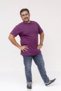 A friendly chubby man wearing glasses, hands on hips and one foot up. Full body photo, wearing purple waffle shirt and jeans,