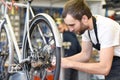 Friendly and competent bicycle mechanic in a workshop repairs a bike