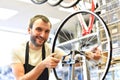 Friendly and competent bicycle mechanic in a workshop repairs a bike