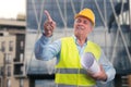 Friendly contractor holding sketches pointing index finger