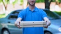 Friendly delivery man giving pizza box, food order online, restaurant service