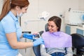 Friendly dentist shows to the patient how to properly brush his teeth with an electric brush. Teeth care and hygiene