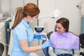 Friendly dentist shows to the patient how to properly brush his teeth with an electric brush. Teeth care and hygiene