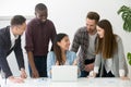 Friendly diverse team working together at laptop in coworking sp