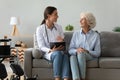 Friendly doctor consulting disabled woman, giving prescription at home Royalty Free Stock Photo