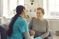 Friendly doctor and happy senior patient sitting on sofa, holding hands and talking Royalty Free Stock Photo