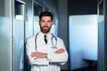 Friendly doctor smiling with crossed arms, man in medical gown, near ward with patient, looking at camera having fun Royalty Free Stock Photo