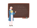 Friendly elderly female school or college teacher, professor, education worker standing beside chalkboard, holding