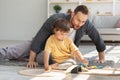 Friendly family concept. Cute little boy playing train with his daddy, surprised man looking at toy with excitement Royalty Free Stock Photo