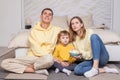 Friendly family, cute parents with child boy son sitting by the bed and holding bowl with popcorn Royalty Free Stock Photo