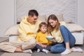 Friendly family, lovely parents with child son sitting by the bed and holding bowl with popcorn Royalty Free Stock Photo