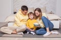 Friendly family, lovely parents in yellow clothes with child son sitting by the bed and eating popcorn