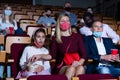 Friendly family in protective masks watching movie in cinema